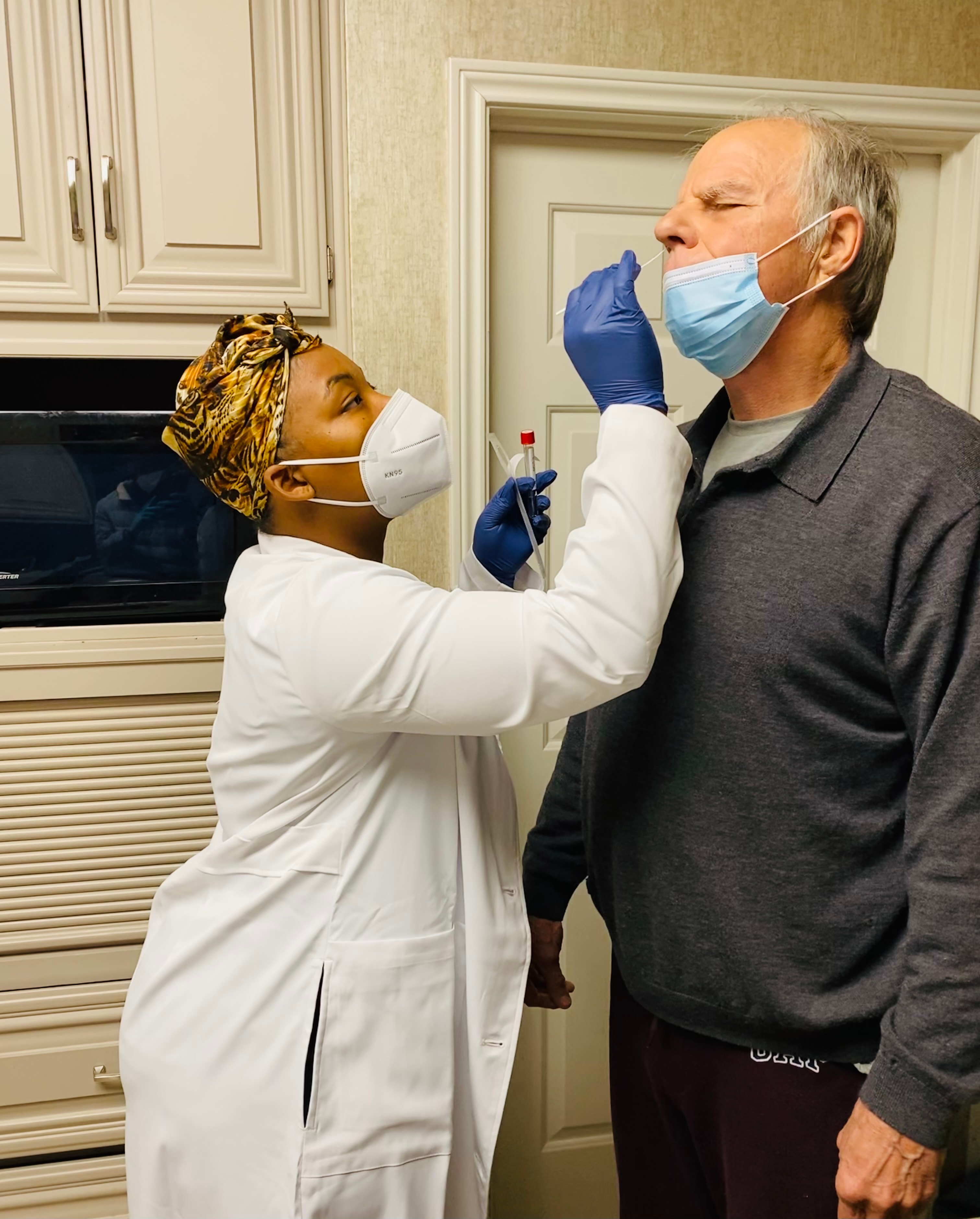 Technician administering COVID-19 nasal swab test to a male patient