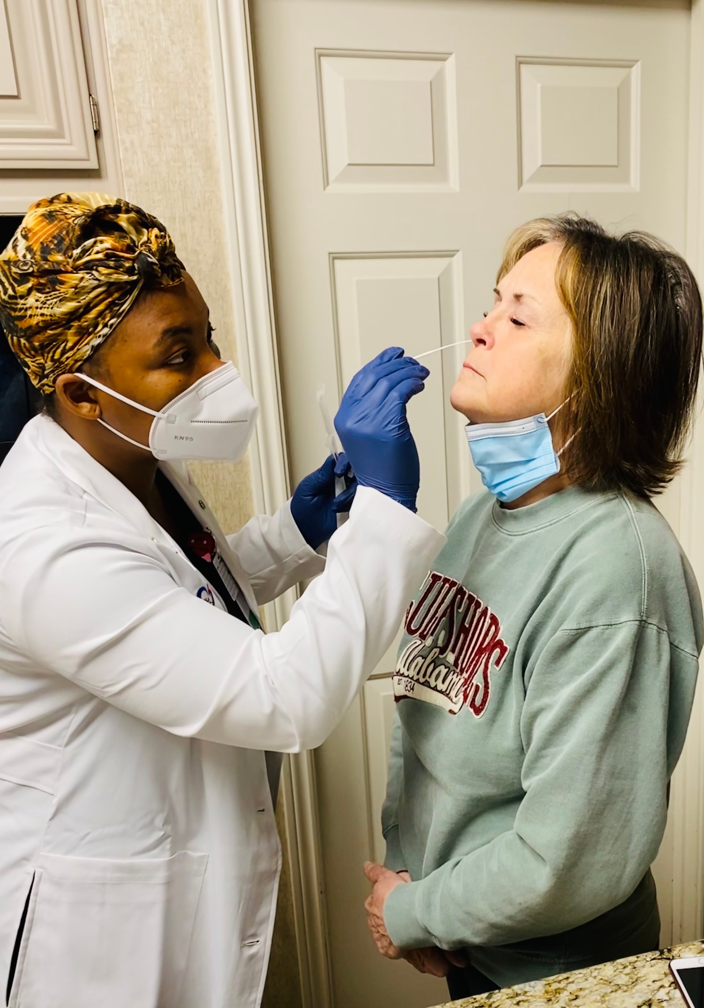 Technician administering COVID-19 nasal swab test to a female patient